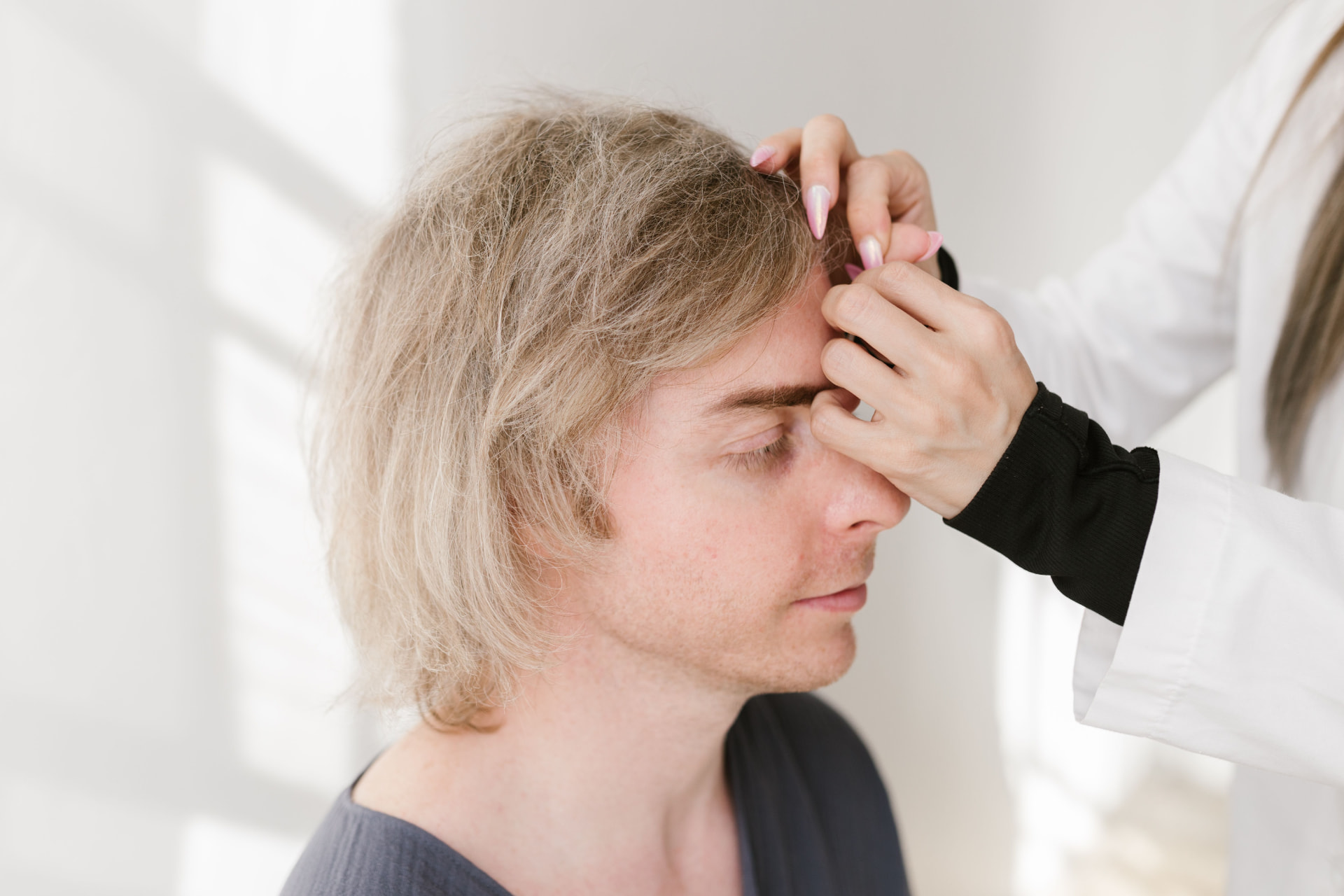 Clinician examining a patient's hairline during a scalp assessment